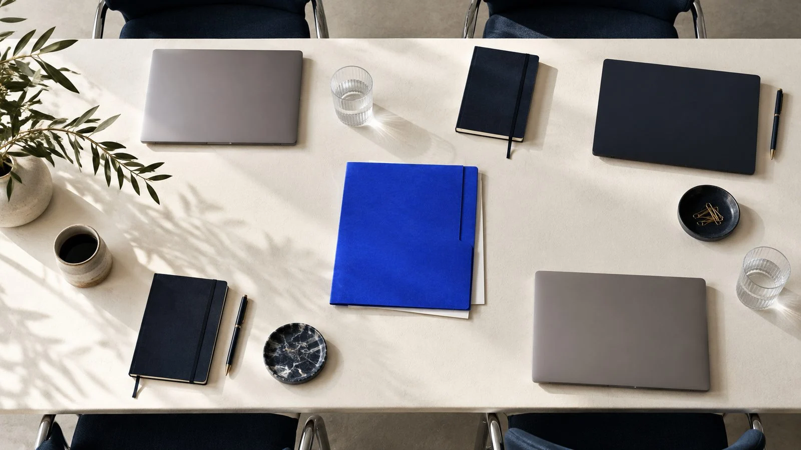 A meeting table from above with laptops and a blue folder.